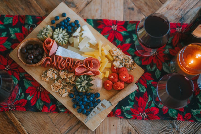 A charcuterie board on a festive table runner at a holiday party.