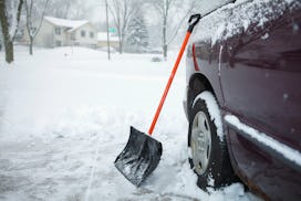 A snow shovel leaning against a car, in a story answering the question, can you shovel snow while pr...
