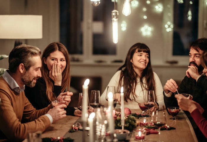Friends enjoying Christmas dinner party at home, in a story about questions to ask at social gatheri...