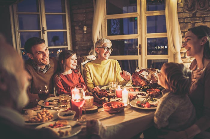 Happy extended family having fun while talking during dinner time at dining table.