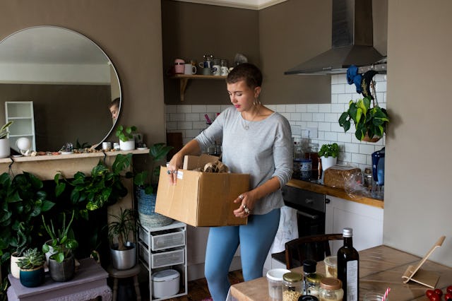 A young woman carrying recycling in her apartment