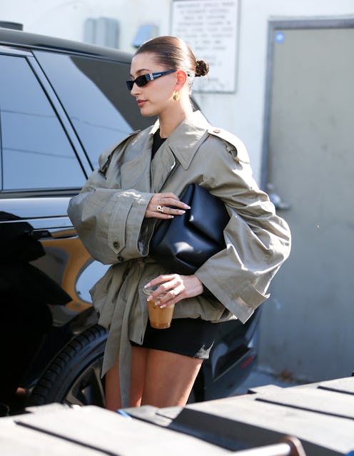 hailey bieber wears a green trench coat with bike shorts