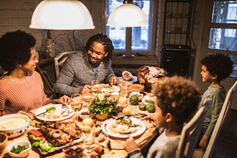 Happy African American family communicating while enjoying in Thanksgiving at dining table.