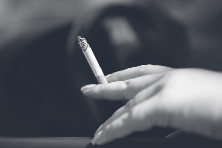 PRODUCTION - 15 August 2023, Saxony, Dresden: A woman sits in a car and holds a cigarette. According...