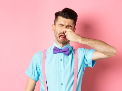 Image of man crying from disgusting smell, shut his nose from awful stink, standing in bow-tie and s...