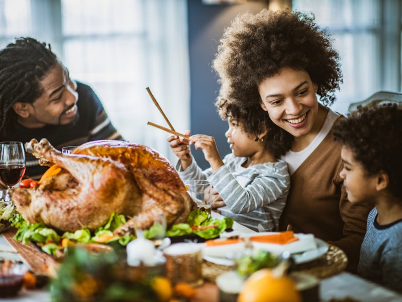 Happy African American family communicating while having Thanksgiving lunch in dining room.