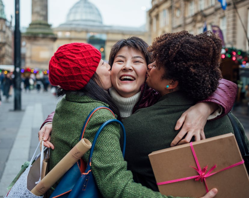 Female friends greeting each other with a hug at a Christmas Market ; what to text during christmas ...