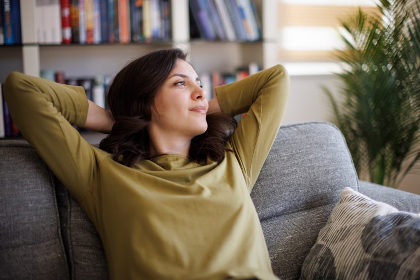 Happy thoughtful young smiling woman relaxing on sofa at home