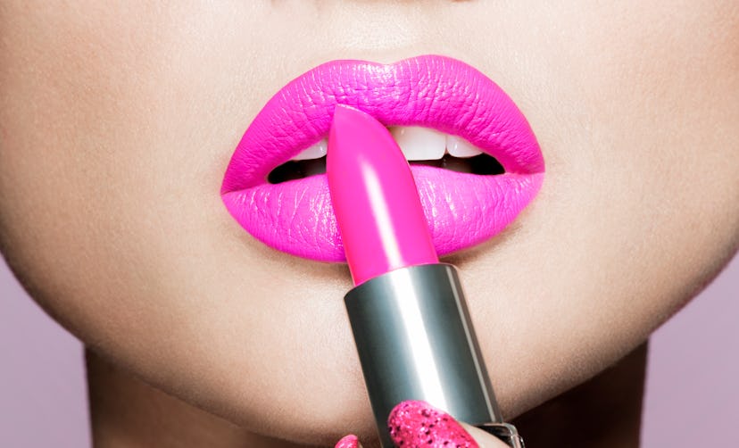 Close up woman applying hot pink lipstick