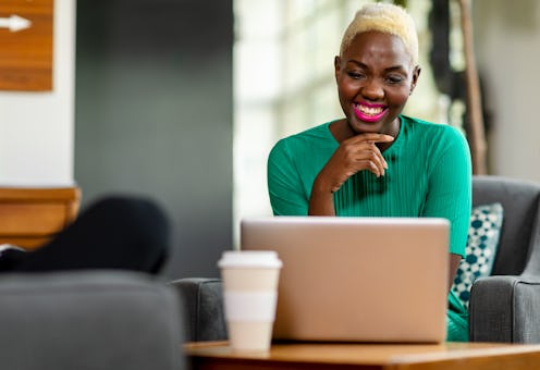 Smiling woman in her 20s working on laptop in creative office