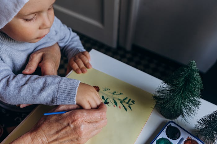 grandmother and grandson paint a Christmas card with watercolors with a picture of a Christmas tree
...