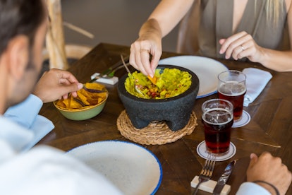 Couple sharing a bowl of guacamole and nachos in a luxury mexican restaurant