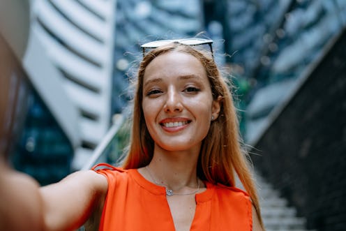 Business woman taking selfie on the phone in front of building