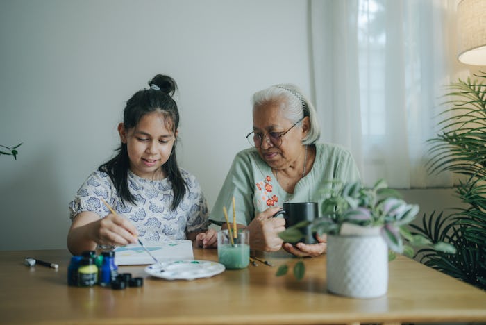 Happy grandmother coloring with her granddaughter at home, in a story answering the question, how do...