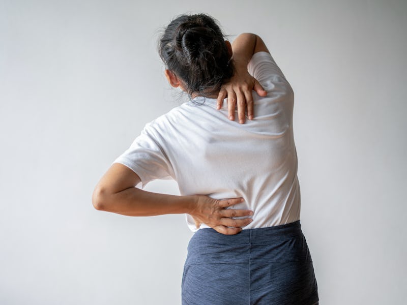 Back view of a woman experiencing pain in her neck and back.
