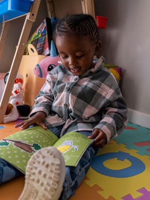 Three-year-old Lethukuthula Bhengu reads a book at her parents' home in Johannesburg on May 13, 2023...