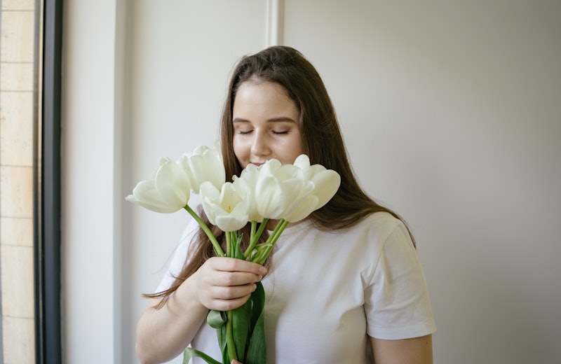 Young smiling woman holding spring white tulip flowers