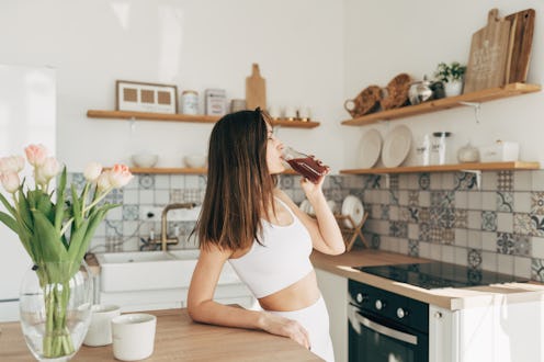 Athletic woman holding friut red detox smoothie after fitness workout. Fitness and healthy lifestyle...