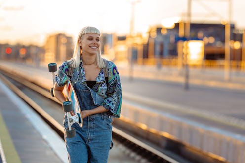 Young woman with blond hair holding longboard on the street