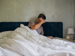 man suffers from a hangover in the morning in bed. He holds his hand on his head. Headache in the mo...