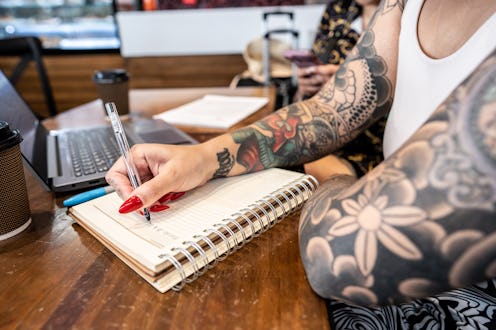 Close-up of a woman taking notes in a notepad at coffee shop