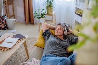 Female relaxing and listening to headphones on sofa.