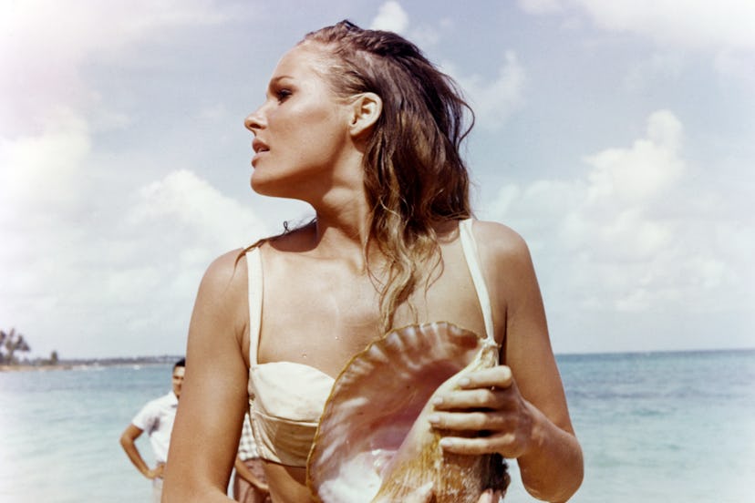 Ursula Andress, Swedish actress, wearing a white bikini and holding a conch shell in a publicity sti...