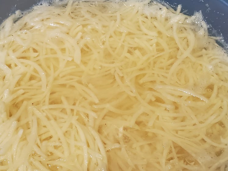 Close-up of shredded potatoes for latkes, or potato pancakes, during preparation of a traditional Je...
