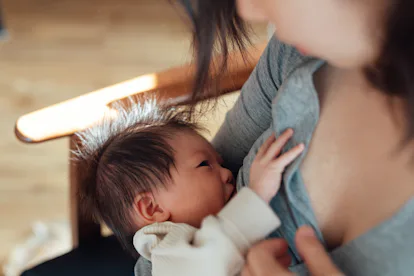 Close up shot of young Asian mother breastfeeding her baby daughter in article about treating RSV in...