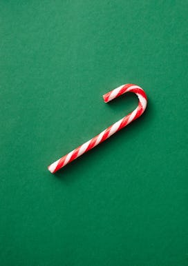 Candy cane over emerald green background. Christmas greeting card.