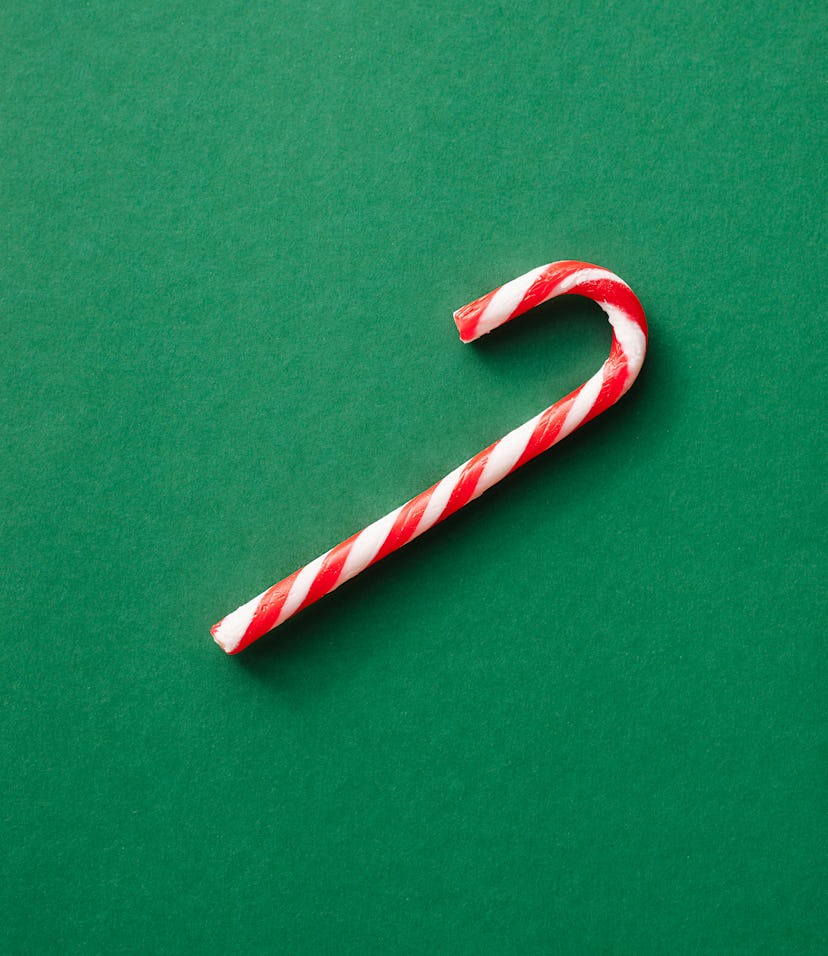 Candy cane over emerald green background. Christmas greeting card.