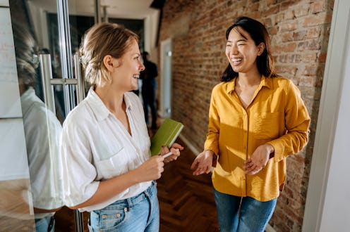 Two female colleagues talking in a hallway of modern office