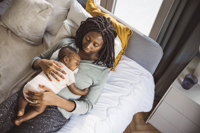 Young mother taking care of her baby son, holding him sleeping, in article about RSV in infants