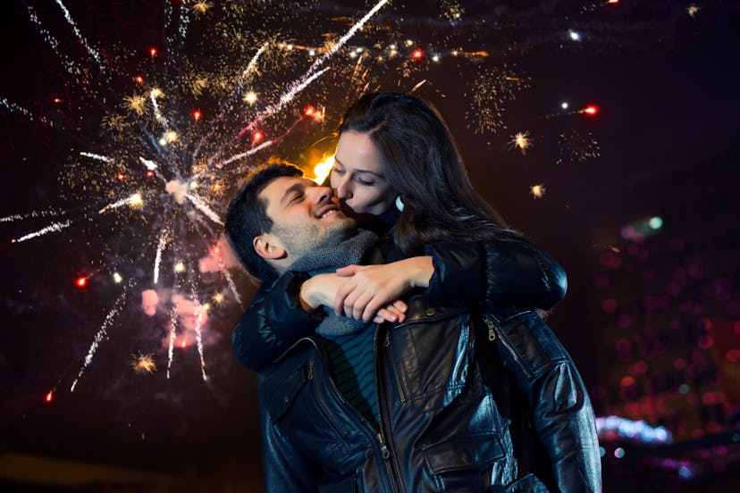 Young couple kissing on New Year's eve. Fireworks in the background. 