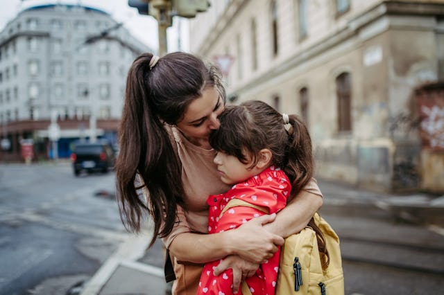 Mother hugging daughter on a city street. Young girl with anxiety doesn't want to go to school. Fear...