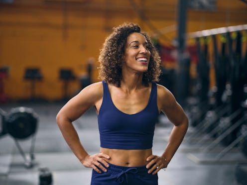 A young adult woman in a gym cross training.