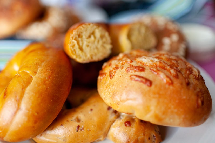 A close-up image shows a variety of bagels piled together on a white plate.