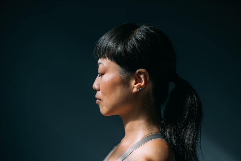 Side view of an Asian woman meditating with eyes closed, a close up.
