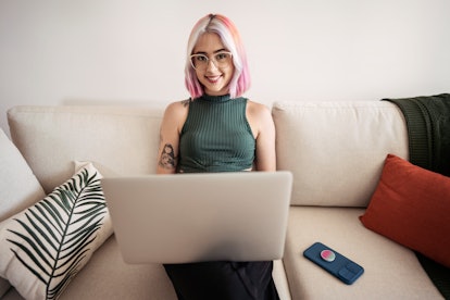 Woman with tattoos and pink hair working at home