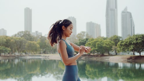 Young Asian woman with smartwatch walking in the park, self care, active healthy lifestyle