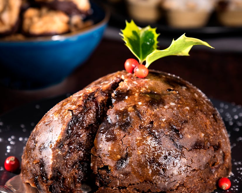 Christmas pudding on a plate in the foreground. There is holly with berries at the top of the Christ...
