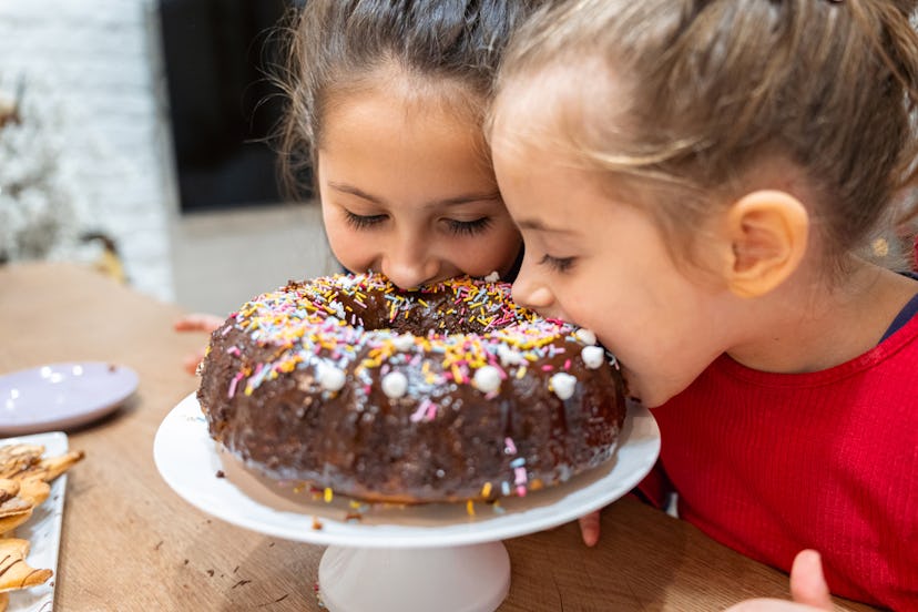 Playful and mischievous sisters biting into a chocolate bundt cake in roundup of captions for pictur...