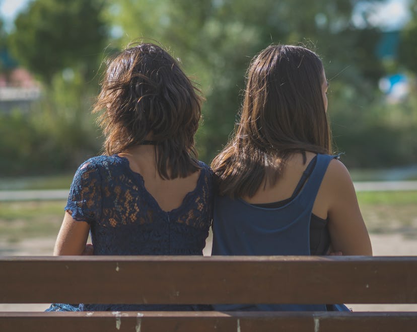 Mother and daughter sitting on a bench arguing and angry at park