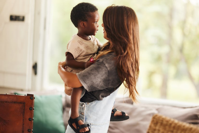 Young single mother holding her adopted African American son at home.