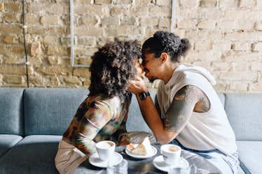 young couple shares a kiss in a cafe as they consider the 2024 love horoscope for their zodiac sign