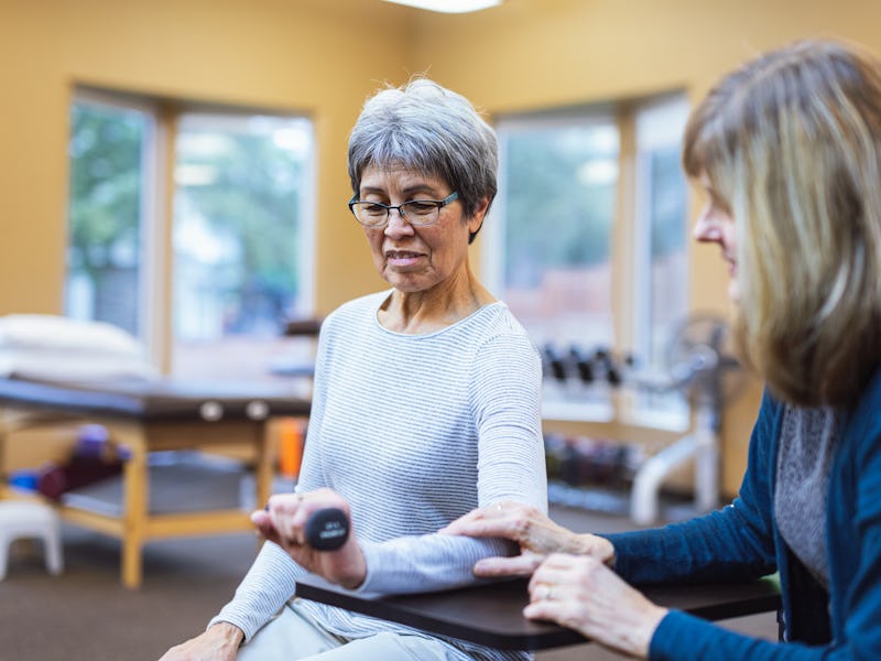 A senior woman of Pacific Islander descent does exercises with a small hand weight to build strength...
