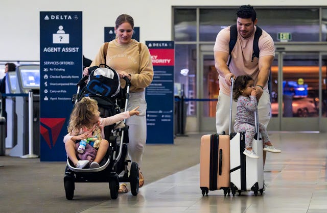 SANTA ANA, CA - November 16: A girl rides on a suitcase as the family heads to their gate at John Wa...