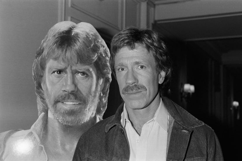 US actor Chuck Norris poses on November 27, 1985 in front of the poster for the movie "Invasion USA"...