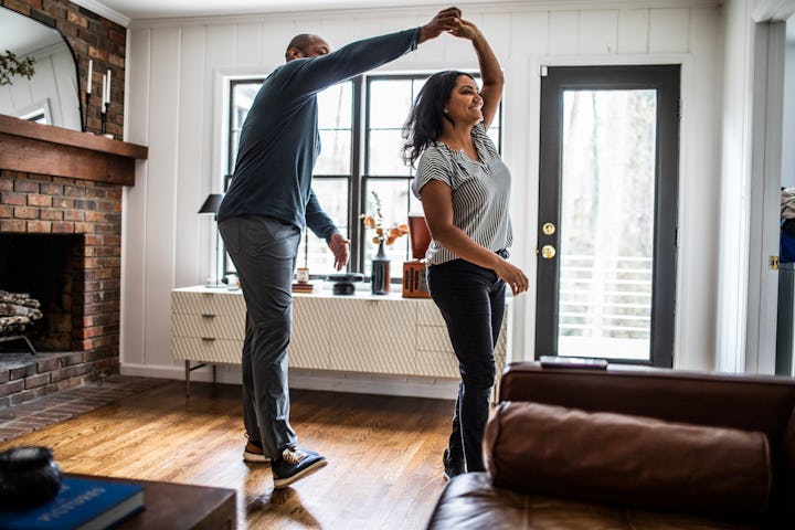 Married couple dancing in living room.