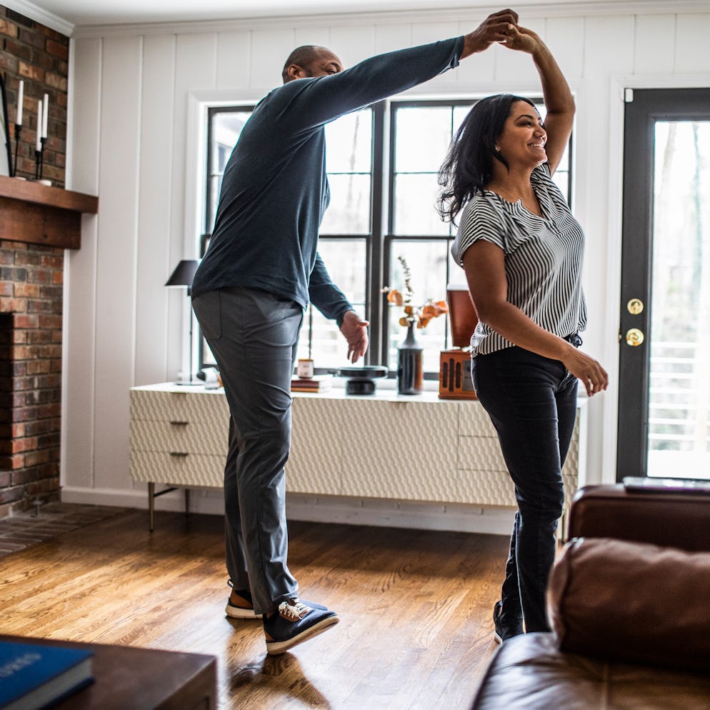 Married couple dancing in living room.